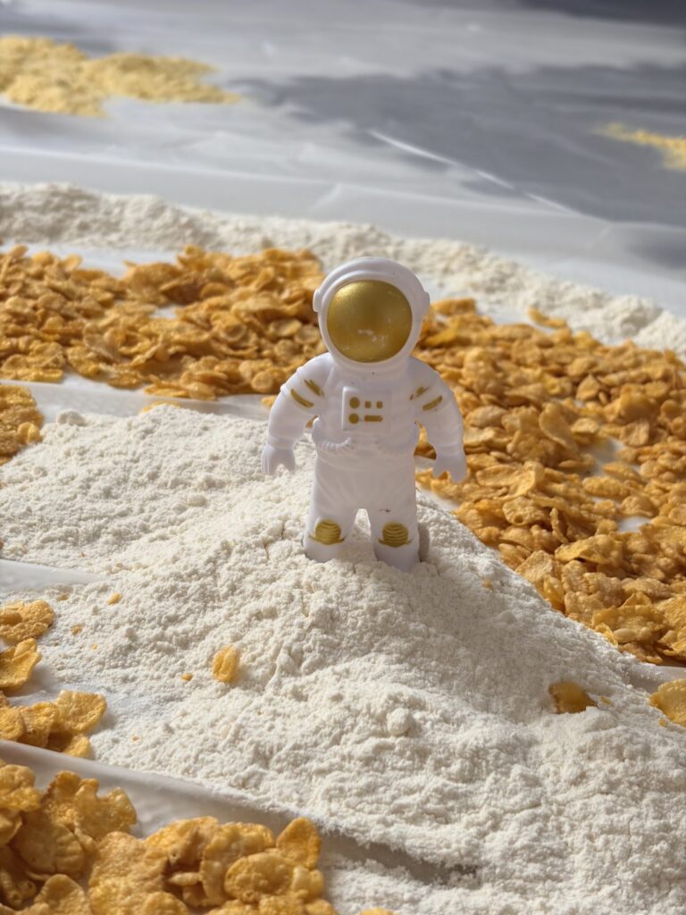 Kosmiczna zabawa sensoryczna — figurka astronauty na mące i makaronie